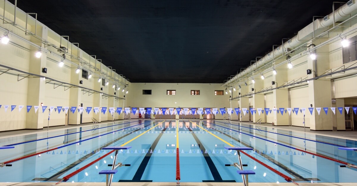 A professional indoor pool with jumping platforms, racing tracks, and blue and white pennants decorating the walls.
